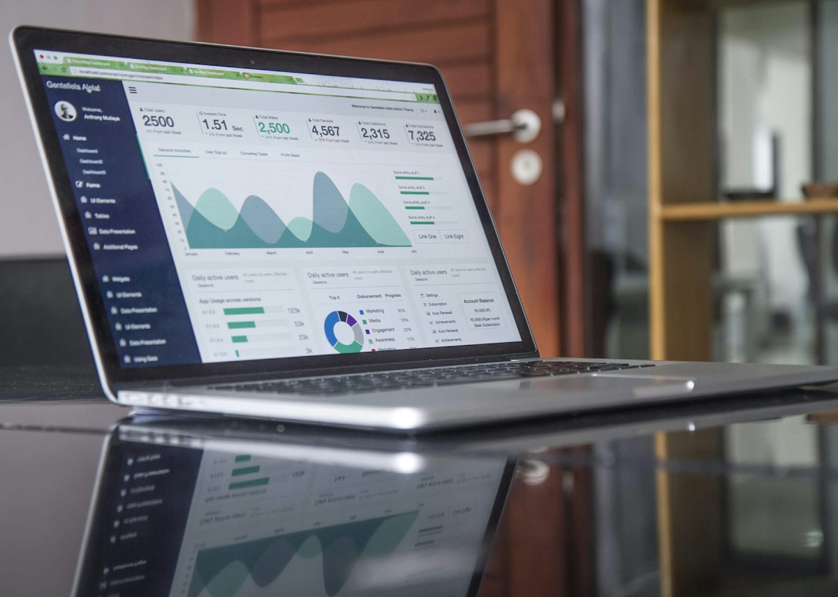 Laptop showing budget spreadsheet next to printed household statements