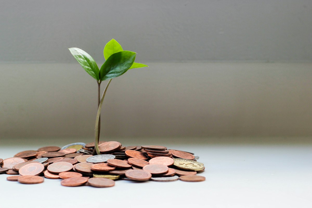 Coins stacked beside a notebook listing savings targets